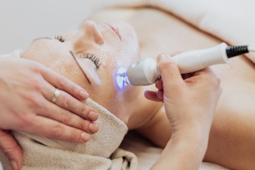 Dermatologist examining patient's skin with modern equipment